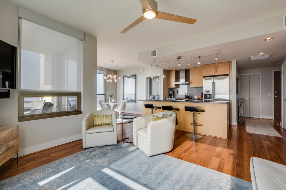 Open concept kitchen - small transitional galley light wood floor open concept kitchen idea in Austin with a double-bowl sink, flat-panel cabinets, light wood cabinets, granite countertops, gray backsplash, porcelain backsplash, stainless steel appliances and an island