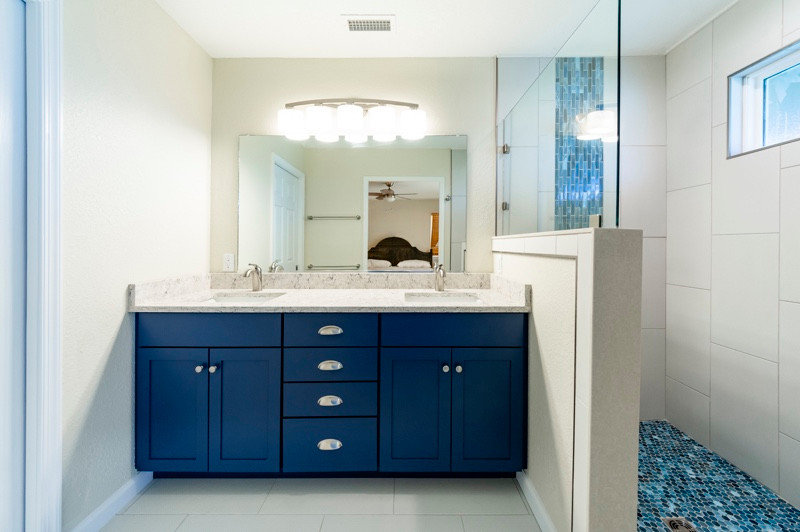 Photo of a beach style master bathroom in Other with a built-in vanity, shaker cabinets, blue cabinets, an alcove shower, white tile, stone tile, white walls, ceramic floors, a drop-in sink, granite benchtops, white floor, beige benchtops, a double vanity and planked wall panelling.
