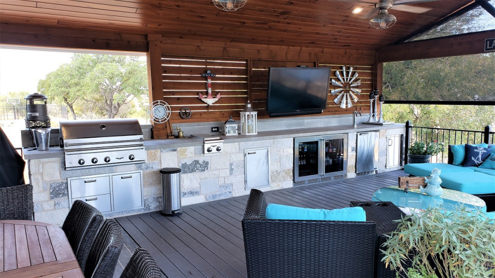 This is an example of an expansive eclectic backyard verandah in Austin with an outdoor kitchen and a roof extension.