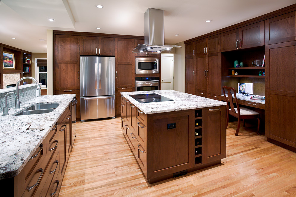 Transitional u-shaped light wood floor enclosed kitchen photo in Calgary with an undermount sink, shaker cabinets, medium tone wood cabinets, granite countertops, beige backsplash, glass tile backsplash, stainless steel appliances and an island