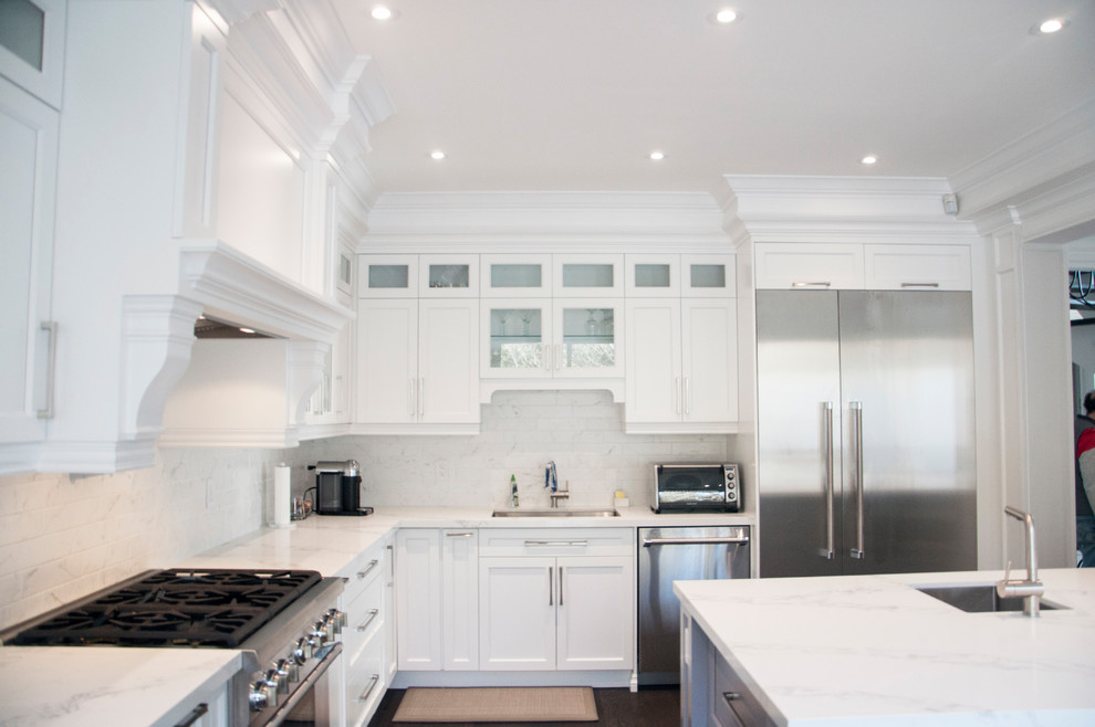 Large transitional l-shaped dark wood floor and brown floor enclosed kitchen photo in Toronto with an undermount sink, shaker cabinets, white cabinets, quartz countertops, white backsplash, marble backsplash, stainless steel appliances, an island and white countertops
