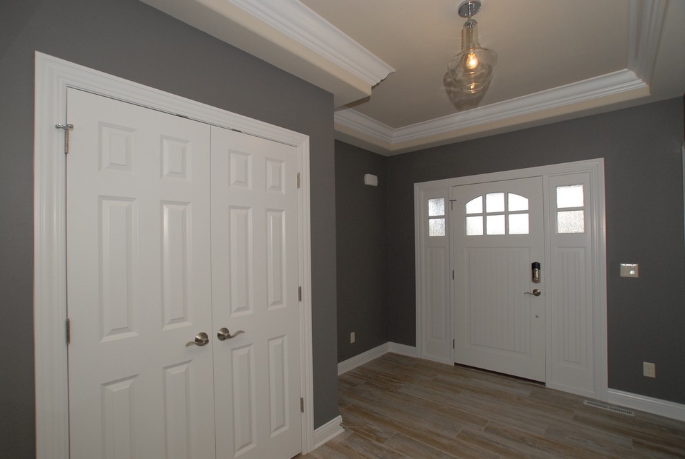 Example of a mid-sized transitional porcelain tile foyer design in Milwaukee with gray walls and a white front door