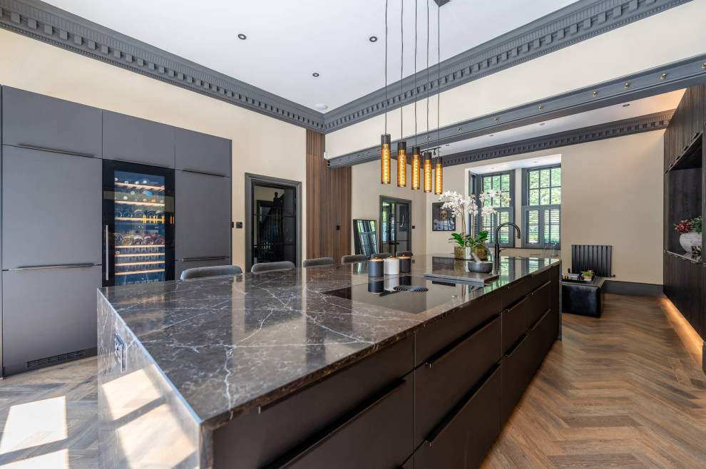 Photo of a large contemporary single-wall open plan kitchen in Hertfordshire with an undermount sink, shaker cabinets, dark wood cabinets, quartzite benchtops, glass sheet splashback, black appliances, medium hardwood floors, with island, brown floor and multi-coloured benchtop.