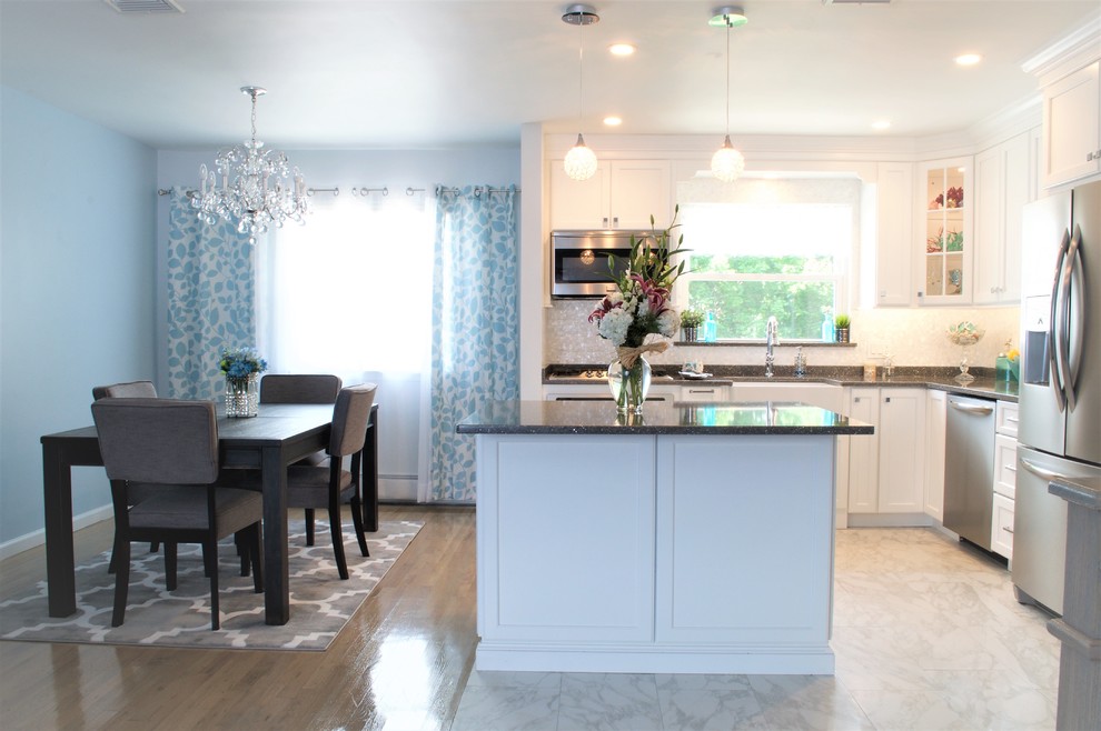 This is an example of a mid-sized transitional l-shaped eat-in kitchen in New York with a farmhouse sink, white cabinets, quartzite benchtops, multi-coloured splashback, stainless steel appliances and with island.
