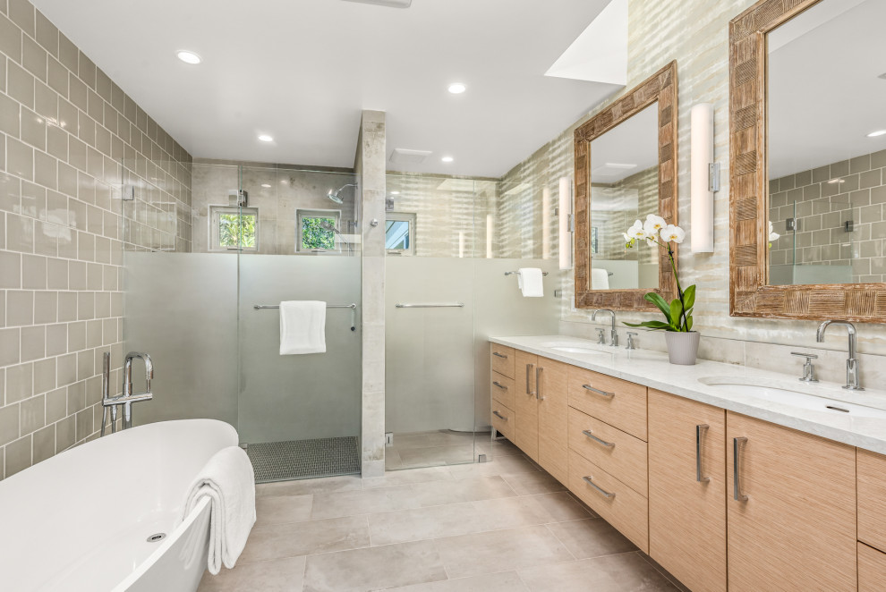 This is an example of a large contemporary ensuite bathroom in San Francisco with flat-panel cabinets, light wood cabinets, a freestanding bath, a built-in shower, a bidet, green tiles, ceramic tiles, multi-coloured walls, porcelain flooring, a submerged sink, engineered stone worktops, grey floors, a hinged door, white worktops, an enclosed toilet, double sinks, a floating vanity unit and wallpapered walls.