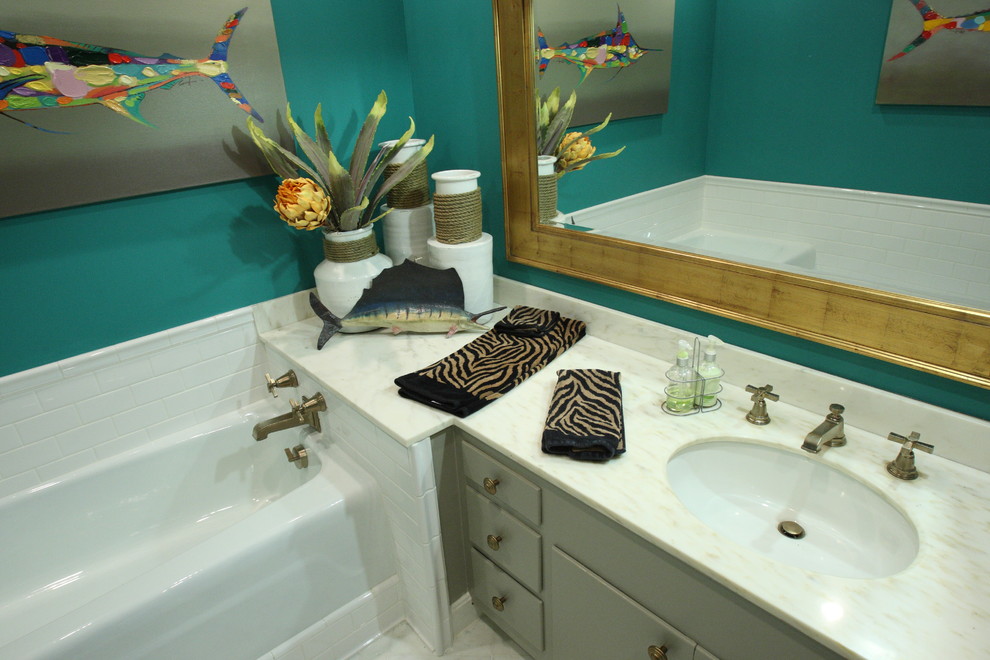 Inspiration for a mid-sized tropical bathroom in Nashville with a drop-in sink, an alcove tub, a one-piece toilet, flat-panel cabinets, grey cabinets, marble benchtops, white tile, subway tile, blue walls and marble floors.