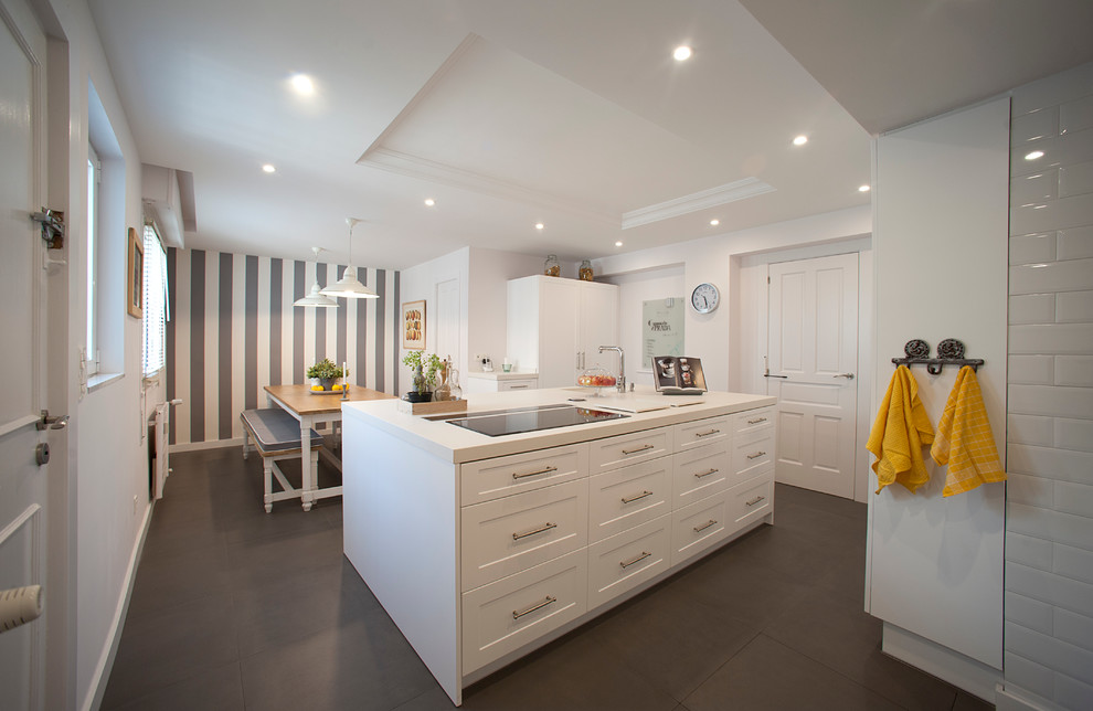 This is an example of a large scandinavian single-wall eat-in kitchen in Bilbao with recessed-panel cabinets, white cabinets, solid surface benchtops, stainless steel appliances, ceramic floors, with island and white benchtop.