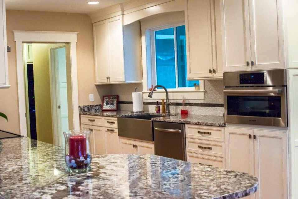 Mid-sized transitional single-wall light wood floor eat-in kitchen photo with a farmhouse sink, recessed-panel cabinets, beige cabinets, granite countertops, white backsplash, matchstick tile backsplash, stainless steel appliances and a peninsula