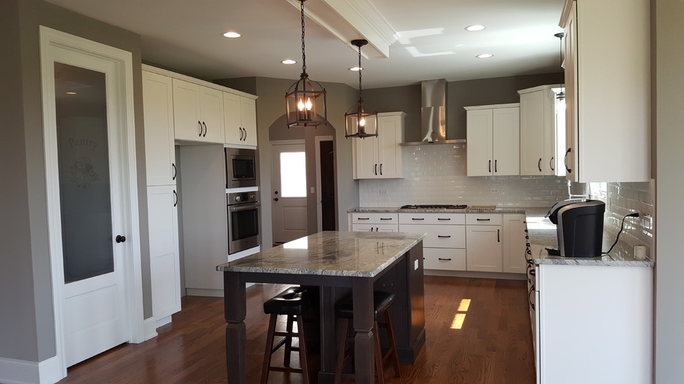 Eat-in kitchen - transitional u-shaped medium tone wood floor eat-in kitchen idea in Chicago with recessed-panel cabinets, white cabinets, granite countertops, white backsplash, porcelain backsplash, stainless steel appliances and an island