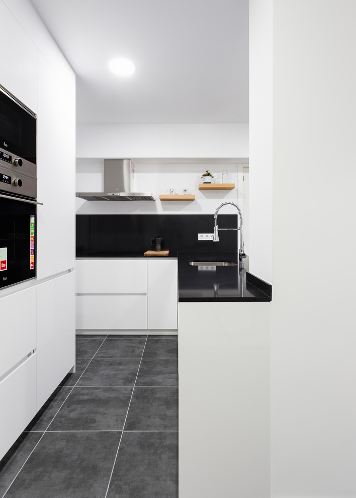 Mid-sized contemporary l-shaped separate kitchen in Other with an undermount sink, flat-panel cabinets, white cabinets, quartz benchtops, black splashback, ceramic floors, a peninsula, black floor and black benchtop.