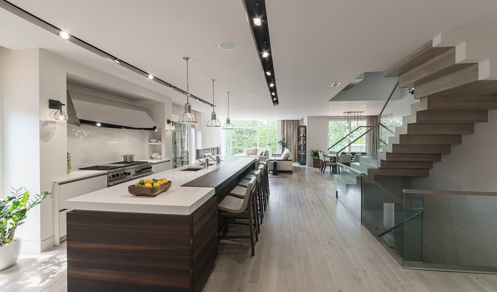 This is an example of a contemporary galley eat-in kitchen in Miami with an undermount sink, stainless steel appliances, flat-panel cabinets, white cabinets, white splashback and stone slab splashback.