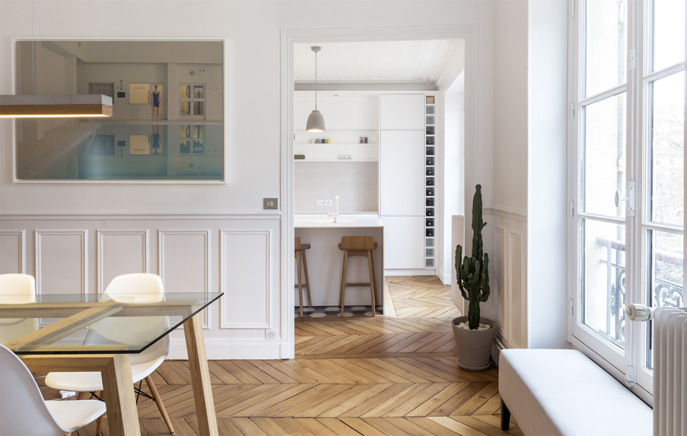 Large contemporary open plan dining in Paris with white walls and light hardwood floors.