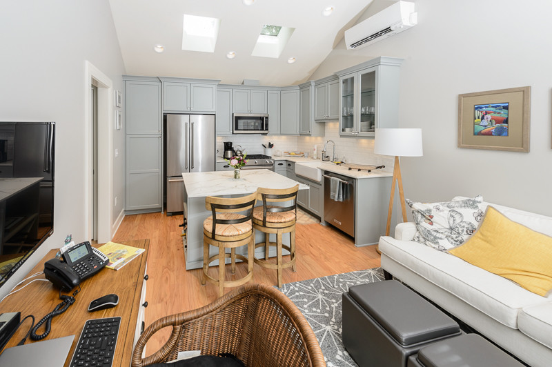 Open concept kitchen - small craftsman l-shaped medium tone wood floor open concept kitchen idea in Portland with a farmhouse sink, shaker cabinets, gray cabinets, quartz countertops, white backsplash, matchstick tile backsplash, stainless steel appliances and an island