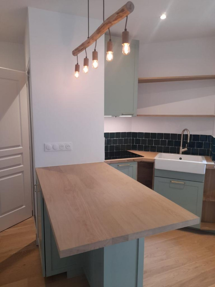 Mid-sized modern l-shaped eat-in kitchen in Paris with an undermount sink, recessed-panel cabinets, turquoise cabinets, wood benchtops, green splashback, ceramic splashback, panelled appliances, medium hardwood floors, multiple islands, brown floor and multi-coloured benchtop.