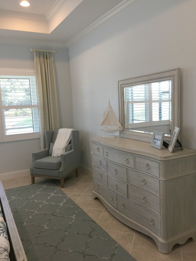 Inspiration for a mid-sized beach style master bedroom in Tampa with grey walls, ceramic floors and beige floor.