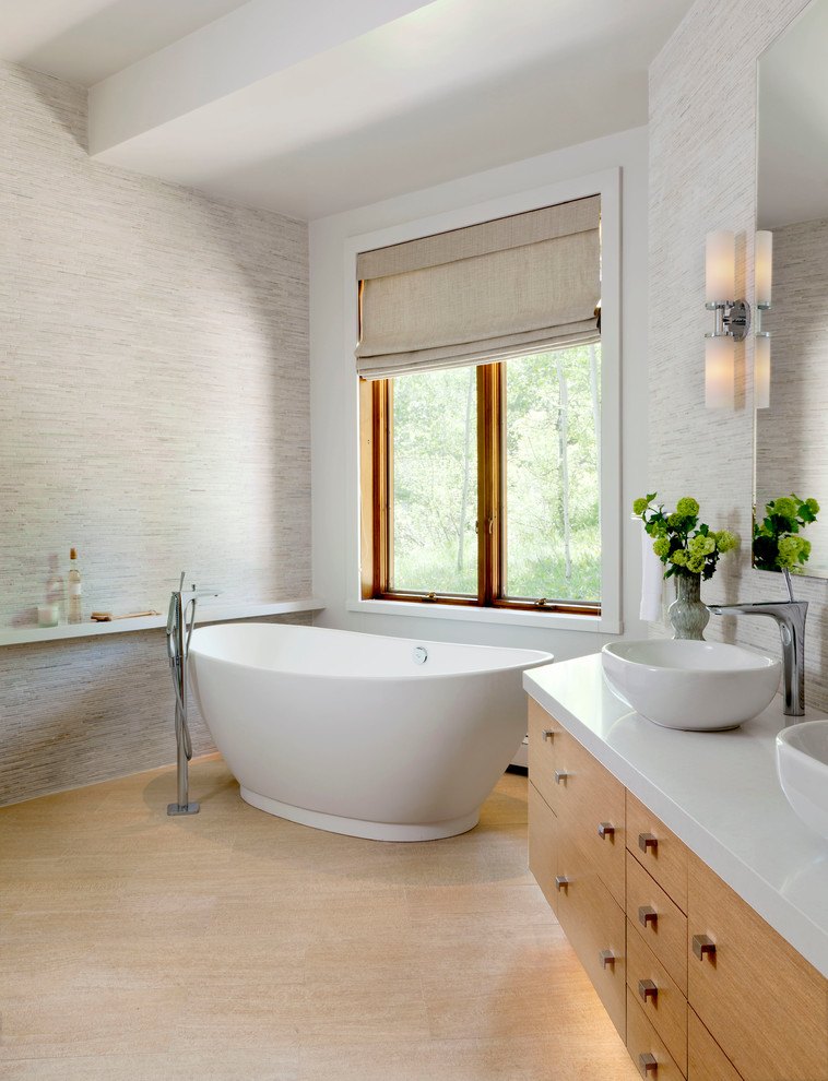 This is an example of a large contemporary master bathroom in Denver with a vessel sink, flat-panel cabinets, light wood cabinets, engineered quartz benchtops, a freestanding tub, an alcove shower, a one-piece toilet, gray tile, white walls and porcelain floors.