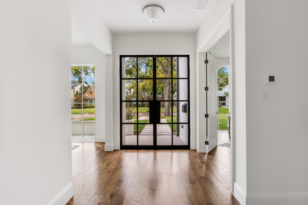 Inspiration for a large transitional medium tone wood floor and brown floor entryway remodel in Dallas with white walls and a black front door