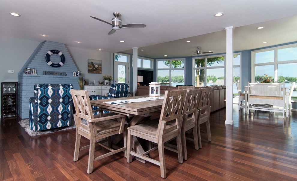 This is an example of a mid-sized beach style open plan dining in Chicago with white walls, medium hardwood floors, a standard fireplace, a brick fireplace surround and brown floor.