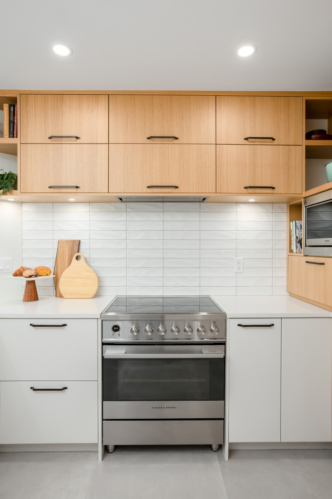 Medium sized contemporary kitchen in Vancouver with flat-panel cabinets, light wood cabinets, white splashback, metro tiled splashback, stainless steel appliances and white worktops.