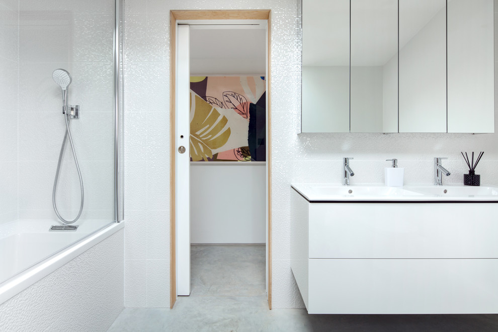 Design ideas for a small contemporary kids bathroom in Sussex with white cabinets, a drop-in tub, a shower/bathtub combo, white tile, ceramic tile, white walls, concrete floors, grey floor, white benchtops and a console sink.