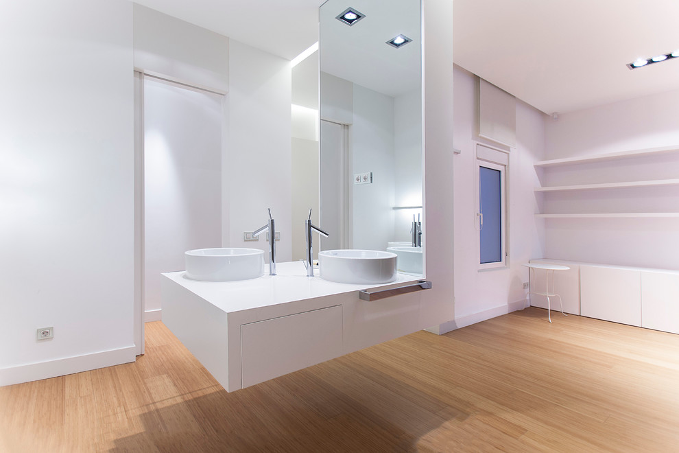 Photo of a large contemporary powder room in Madrid with open cabinets, white cabinets, white walls, light hardwood floors, a vessel sink and solid surface benchtops.