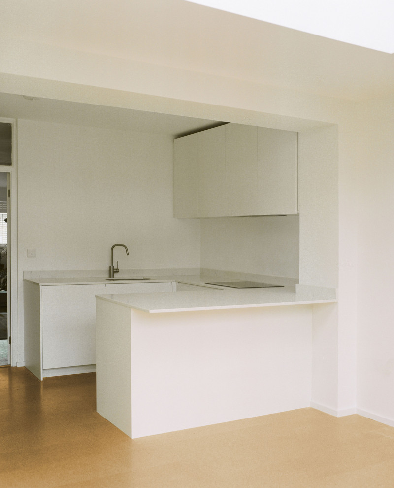 Foto di una cucina contemporanea di medie dimensioni con lavello integrato, ante lisce, ante bianche, top in legno, elettrodomestici in acciaio inossidabile, pavimento in sughero e penisola