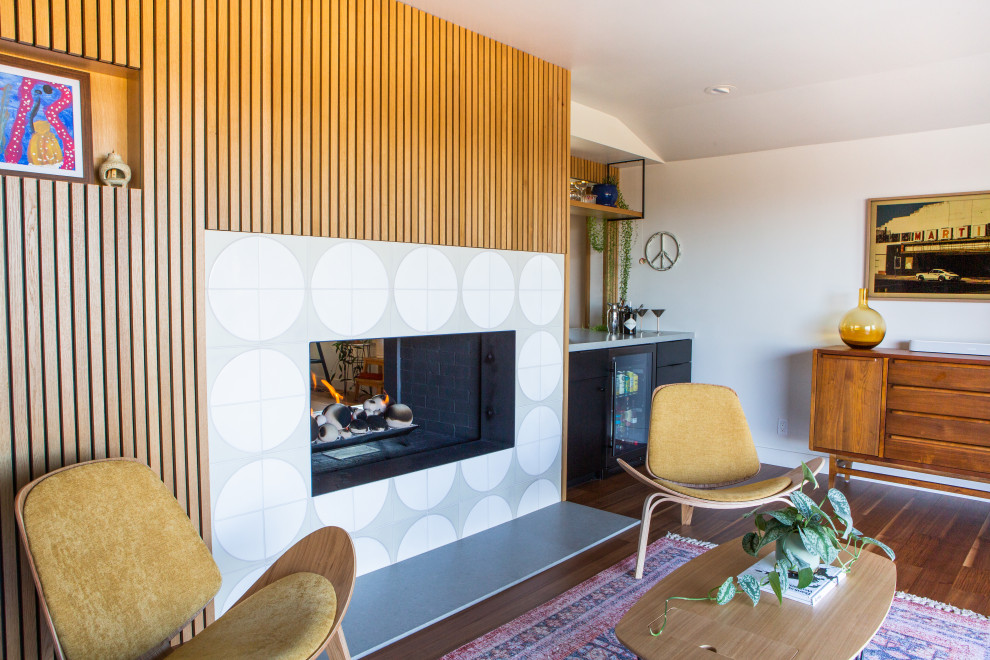 This is an example of a large retro living room in San Francisco with a two-sided fireplace and a tiled fireplace surround.