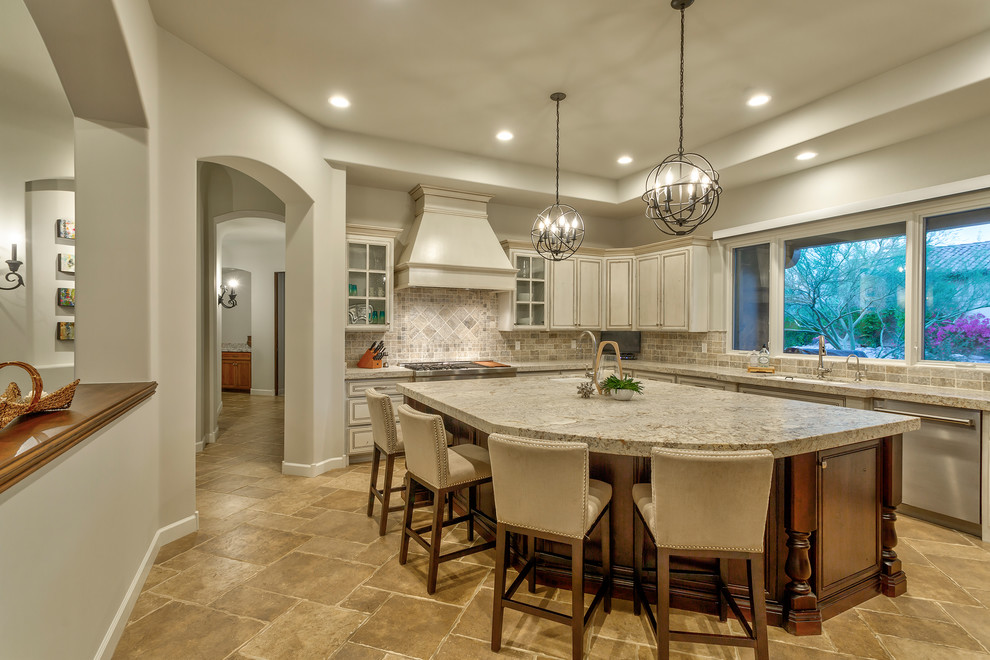 Inspiration for a mid-sized l-shaped travertine floor and multicolored floor eat-in kitchen remodel in Phoenix with a drop-in sink, recessed-panel cabinets, distressed cabinets, granite countertops, multicolored backsplash, travertine backsplash, stainless steel appliances, an island and multicolored countertops