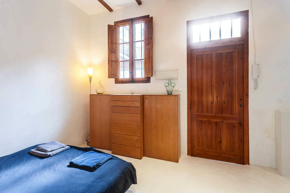 Foto de dormitorio tipo loft mediterráneo pequeño con paredes blancas, suelo de cemento, suelo blanco y vigas vistas