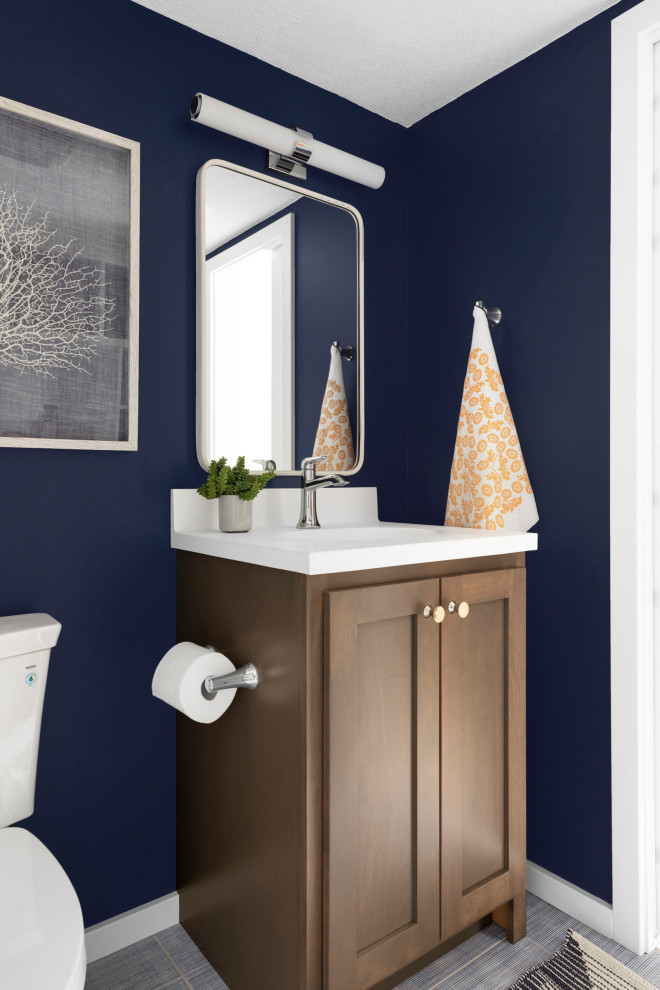 Cette photo montre un petit WC et toilettes bord de mer en bois brun avec un placard à porte shaker, WC séparés, un carrelage bleu, des carreaux de céramique, un mur bleu, un sol en carrelage de porcelaine, un lavabo intégré, un plan de toilette en surface solide, un sol bleu, un plan de toilette blanc et meuble-lavabo sur pied.