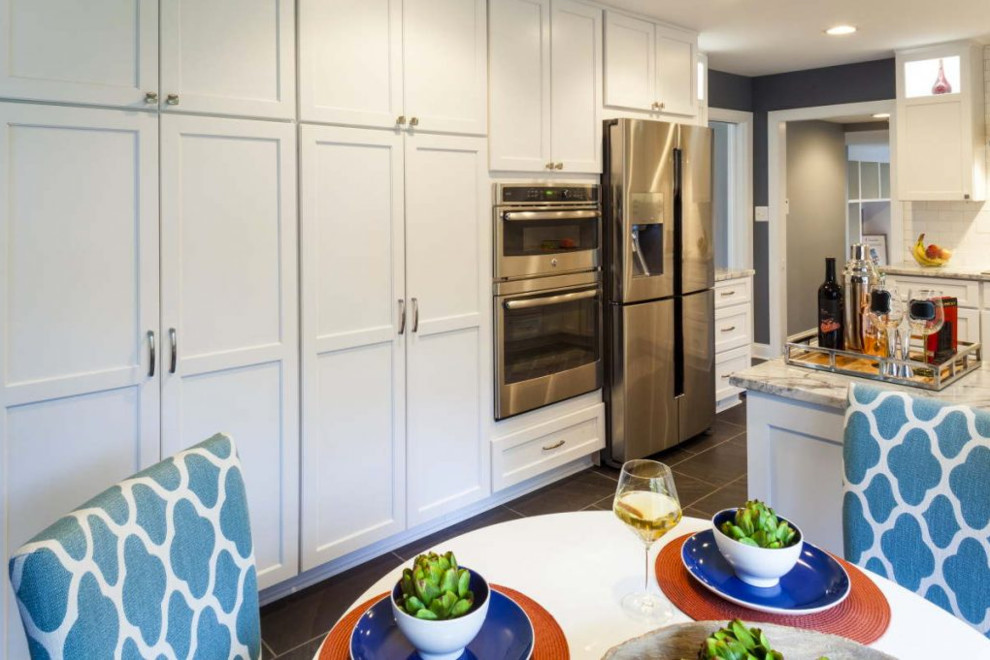 This is an example of a mid-sized transitional u-shaped separate kitchen in Los Angeles with stainless steel appliances, grey floor, a single-bowl sink, recessed-panel cabinets, white cabinets, marble benchtops, white splashback, subway tile splashback, slate floors and a peninsula.