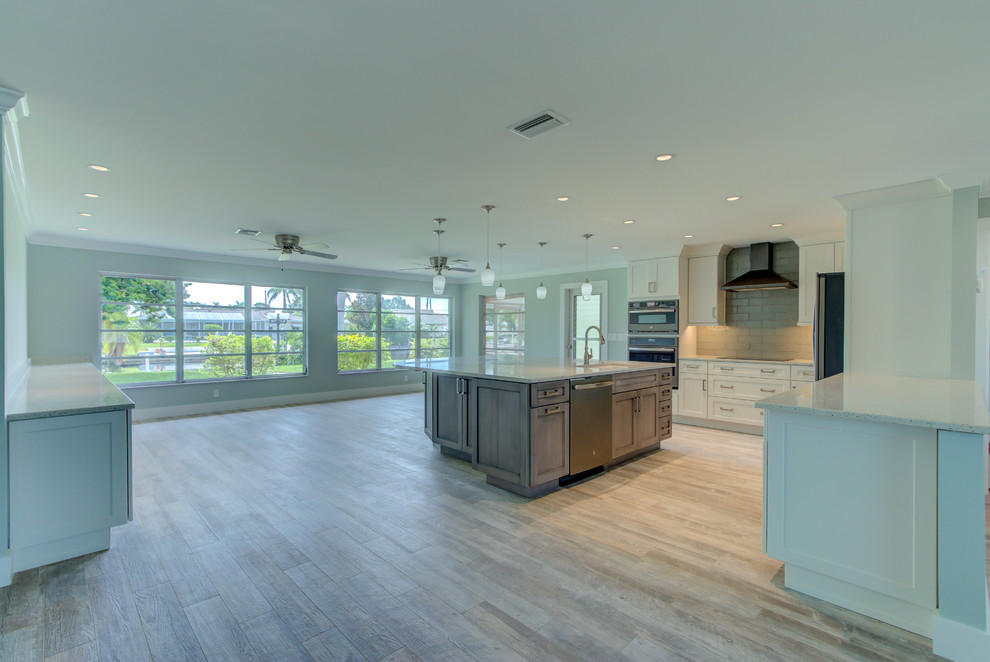 Home design - large transitional l-shaped ceramic tile and gray floor home design idea with an undermount sink, shaker cabinets, white cabinets, recycled glass countertops, blue backsplash, glass tile backsplash, stainless steel appliances, an island and white countertops