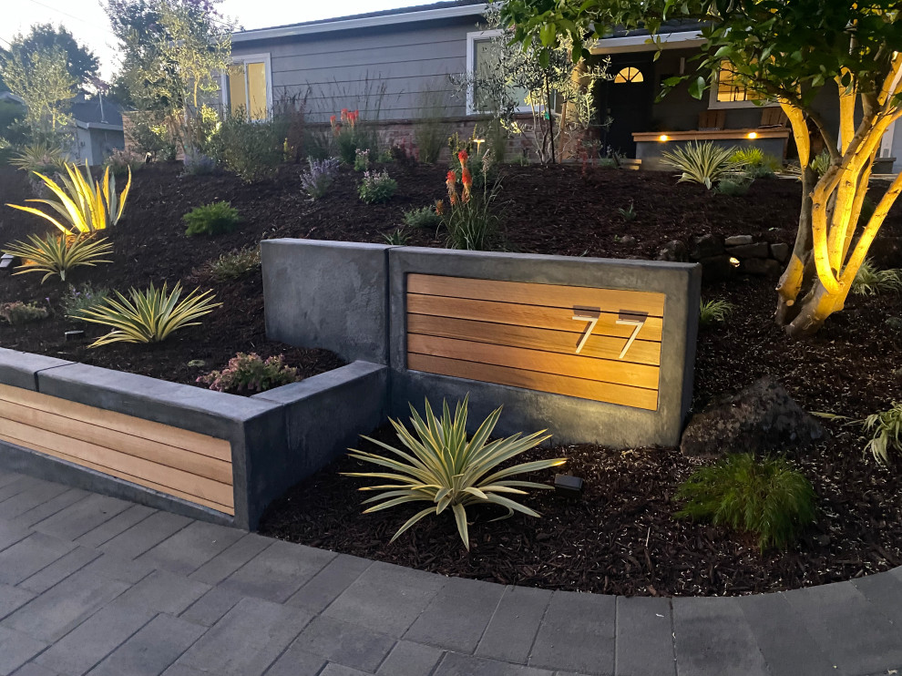 This is an example of a mid-sized modern front yard full sun driveway in San Francisco with a retaining wall and concrete pavers.