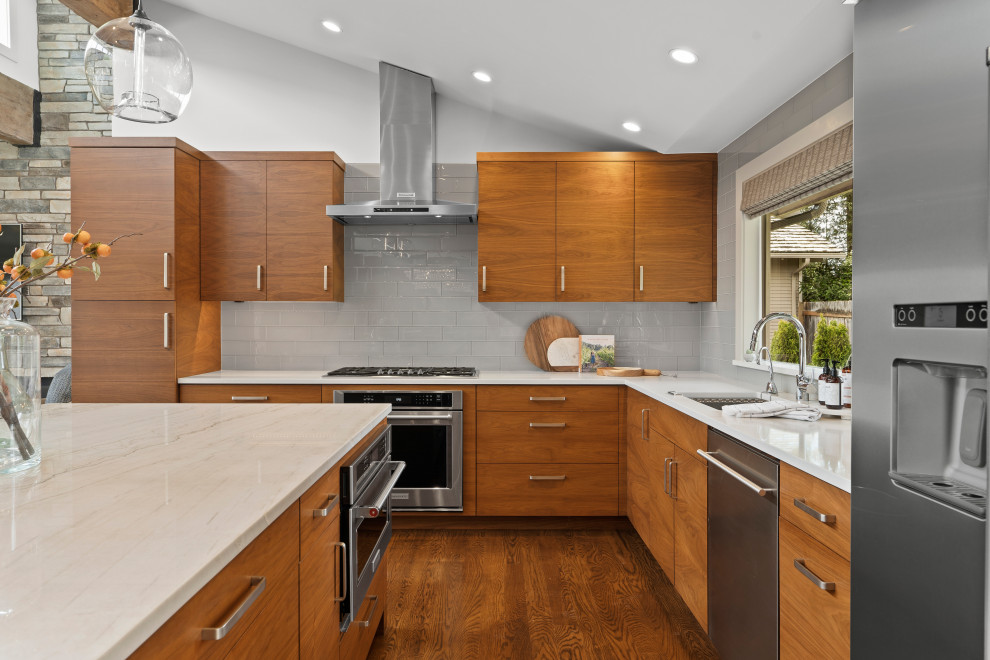 Inspiration for a contemporary l-shaped kitchen in Seattle with an undermount sink, flat-panel cabinets, medium wood cabinets, grey splashback, stainless steel appliances, dark hardwood floors, with island, brown floor, white benchtop and vaulted.