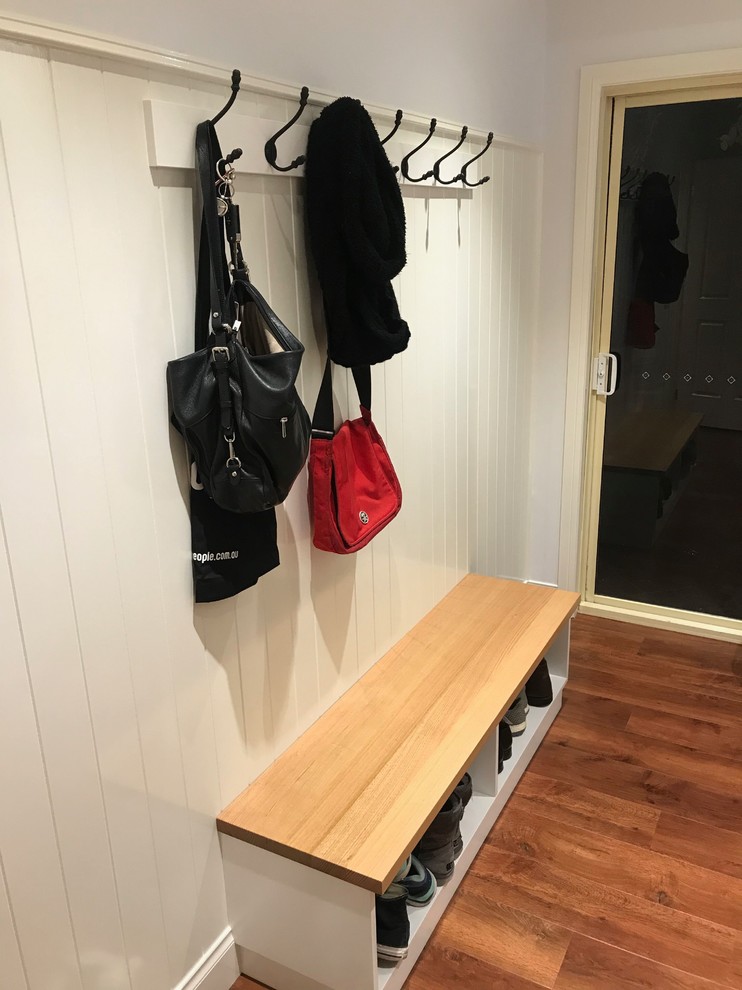 This is an example of a mid-sized traditional galley utility room in Melbourne with a drop-in sink, shaker cabinets, white cabinets, granite benchtops, white walls, medium hardwood floors, a side-by-side washer and dryer and white benchtop.