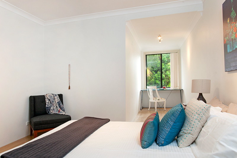 Small beach style master bedroom in Sydney with white walls and light hardwood floors.