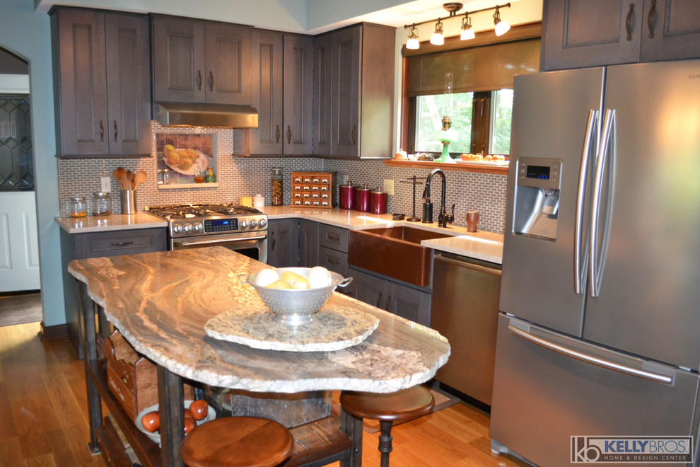 This is an example of a mid-sized country l-shaped eat-in kitchen in Cincinnati with a farmhouse sink, shaker cabinets, grey cabinets, quartz benchtops, grey splashback, mosaic tile splashback, stainless steel appliances, light hardwood floors and with island.