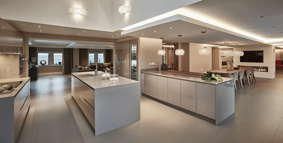 This is an example of an expansive contemporary open plan kitchen in Other with flat-panel cabinets, quartzite benchtops, mirror splashback, porcelain floors, beige cabinets, brown splashback, stainless steel appliances, with island, beige floor and beige benchtop.