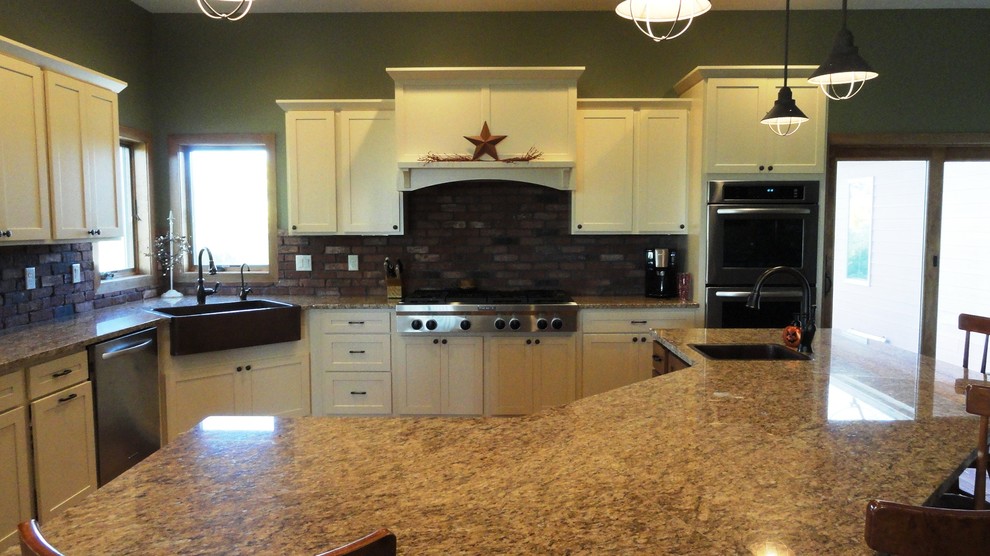 Open concept kitchen - large l-shaped open concept kitchen idea with a farmhouse sink, flat-panel cabinets, white cabinets, granite countertops, stainless steel appliances, green walls and an island