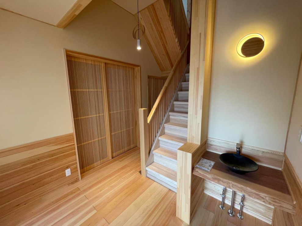This is an example of a hallway in Other with light hardwood floors, wallpaper and wood walls.