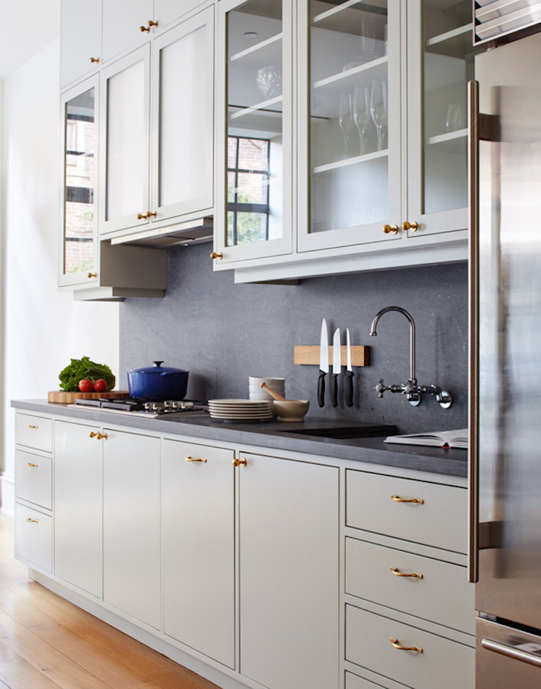 This is an example of a mid-sized traditional galley eat-in kitchen in New York with flat-panel cabinets, grey splashback, brown floor, no island, concrete benchtops, an integrated sink, grey cabinets, stone slab splashback and medium hardwood floors.