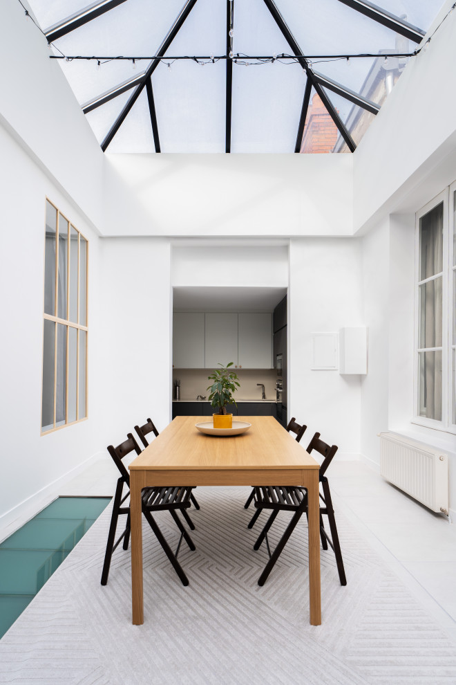 Photo of a mid-sized modern open plan dining in Paris with white walls, a corner fireplace, white floor and vaulted.