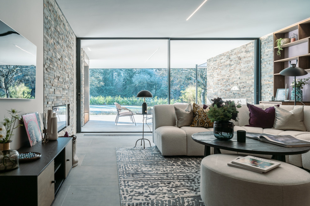 На фото: гостиная комната в современном стиле с серыми стенами, телевизором на стене и серым полом с