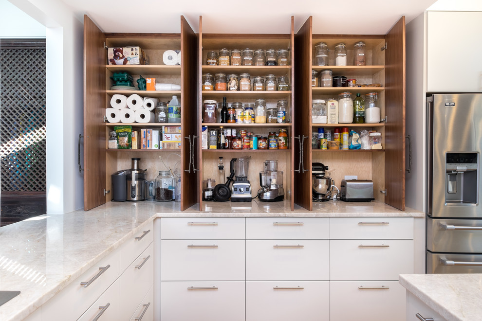 Design ideas for a large transitional l-shaped kitchen pantry in Portland with flat-panel cabinets, medium wood cabinets, quartzite benchtops, white splashback, ceramic splashback, stainless steel appliances and with island.