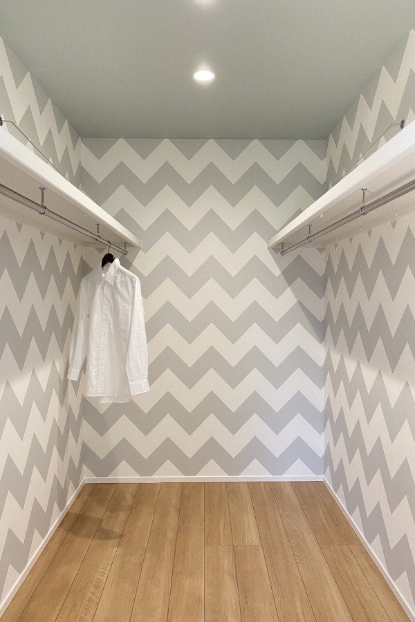 Immagine di una cabina armadio unisex con pavimento in legno massello medio e soffitto in carta da parati