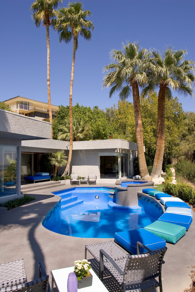 Photo of a tropical backyard custom-shaped pool in Los Angeles with concrete slab.
