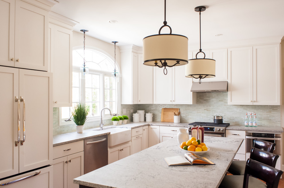 Large transitional single-wall medium tone wood floor open concept kitchen photo in Philadelphia with a farmhouse sink, shaker cabinets, white cabinets, limestone countertops, green backsplash, white appliances and an island