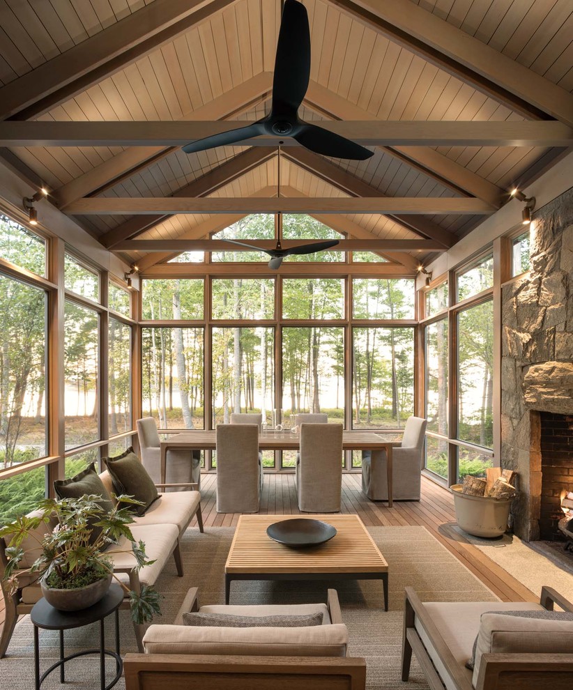 This is an example of a large contemporary sunroom in Portland Maine with medium hardwood floors, a standard fireplace and a stone fireplace surround.