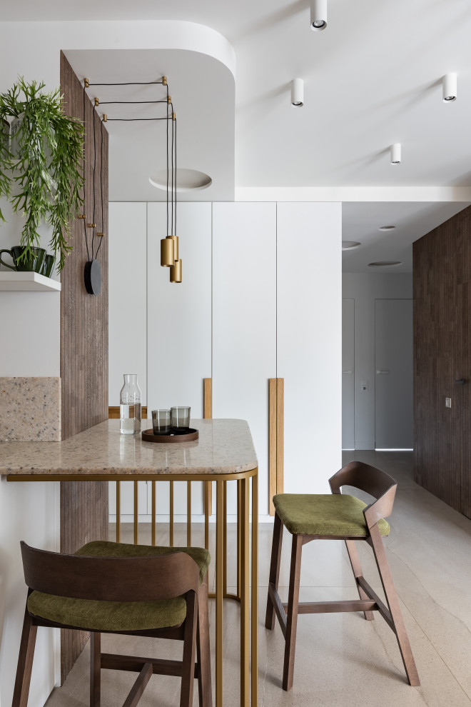 Inspiration for a small contemporary l-shaped eat-in kitchen in Saint Petersburg with an undermount sink, flat-panel cabinets, white cabinets, solid surface benchtops, beige splashback, engineered quartz splashback, white appliances, porcelain floors, with island, beige floor, beige benchtop and recessed.