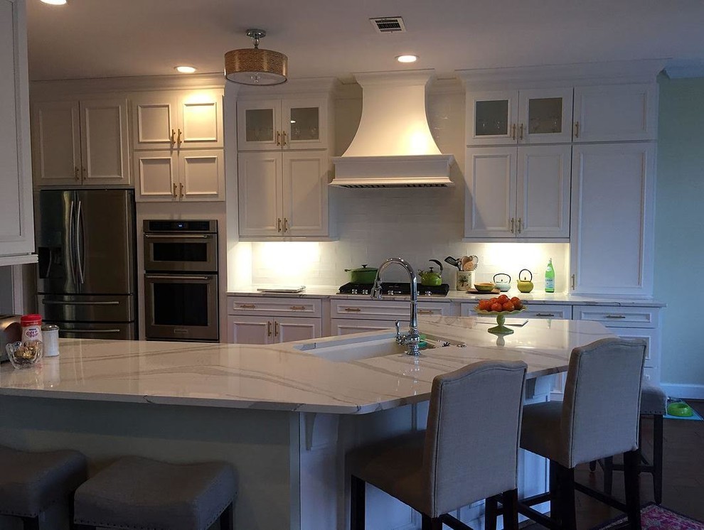 Eat-in kitchen - mid-sized transitional single-wall dark wood floor and brown floor eat-in kitchen idea in Atlanta with an undermount sink, recessed-panel cabinets, white cabinets, marble countertops, white backsplash, subway tile backsplash, stainless steel appliances and a peninsula